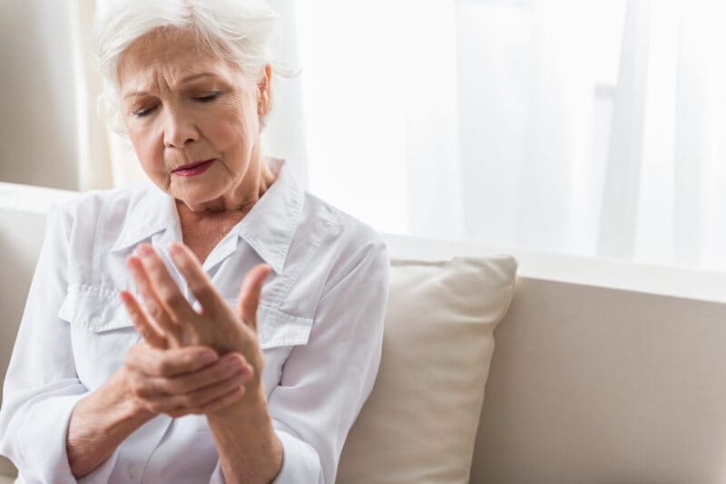 older woman in need of a steroid injection holds her painful hand