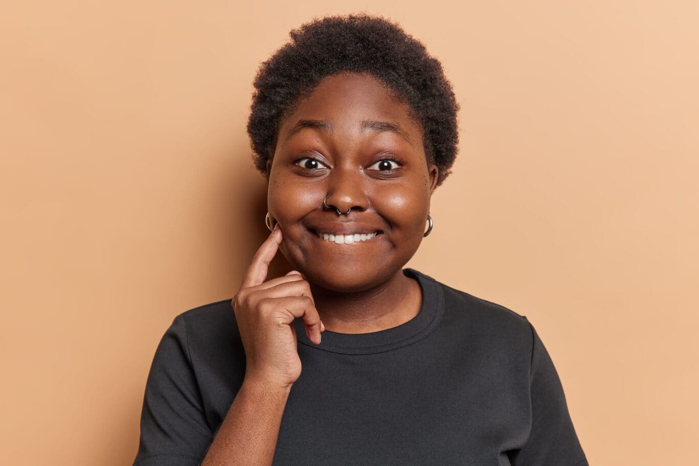 A woman with a smiling face pointing to the need for buccal fat pad reduction