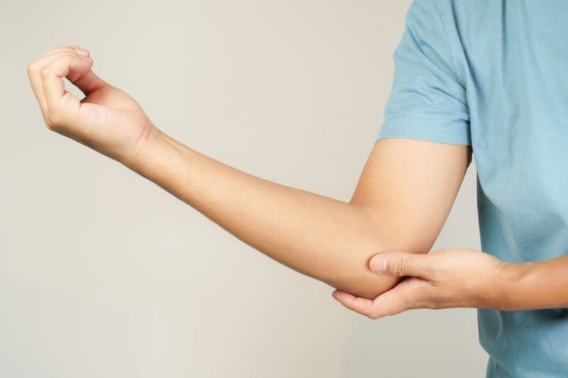A person holding a painful elbow as a result of cubital tunnel syndrome
