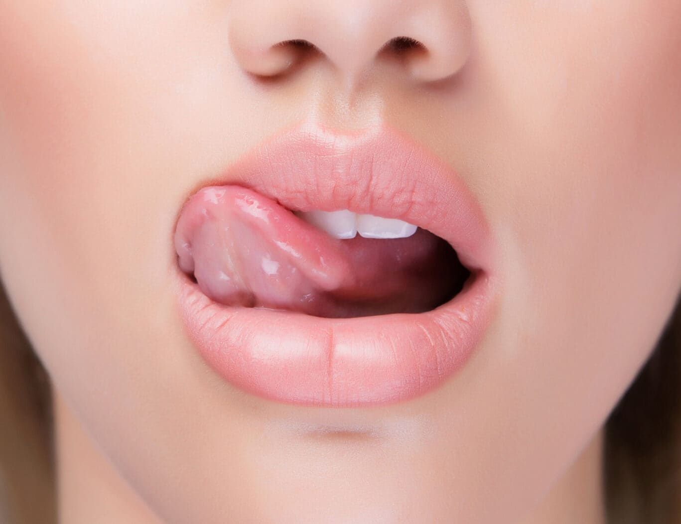 Close-up of a person's face showing their mouth slightly open and their tongue licking their upper lip, highlighting features that might interest a plastic surgery specialist.