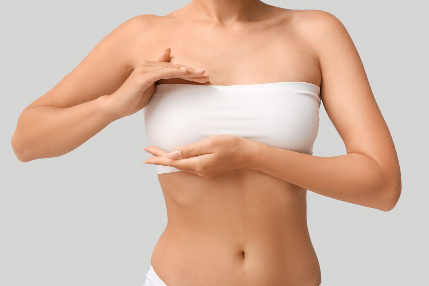 Young woman in bandeau top with beautiful breasts on grey background