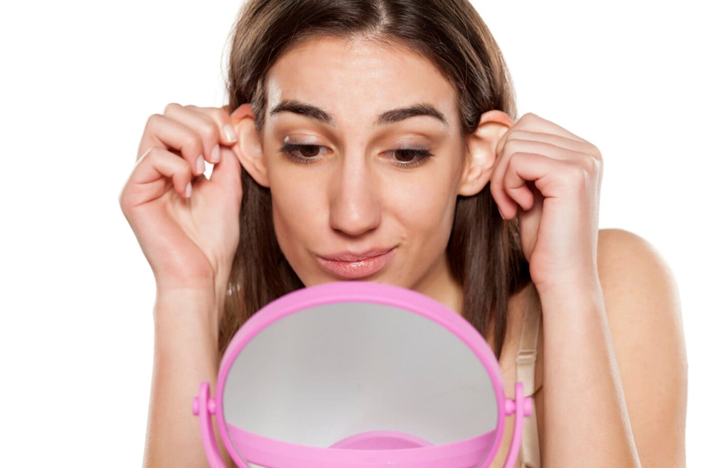 beautiful young woman looks at her ears in front of the mirror